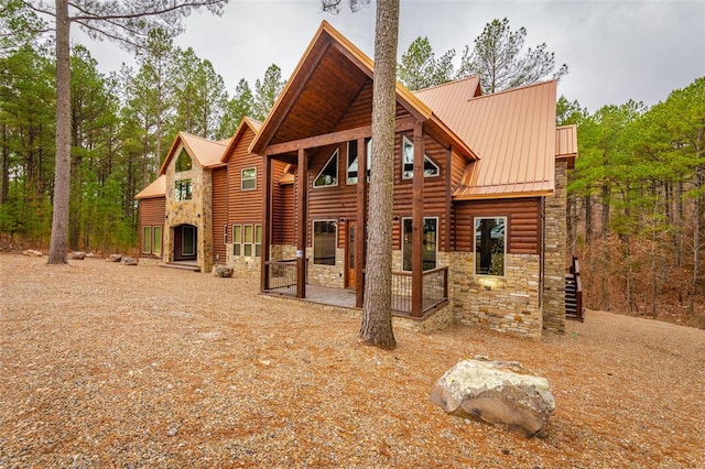 exterior space featuring stone siding, faux log siding, and metal roof