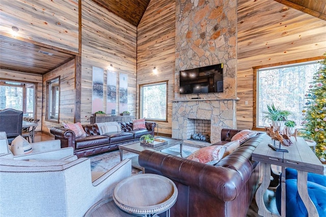 living area with plenty of natural light, wood ceiling, wooden walls, and a stone fireplace