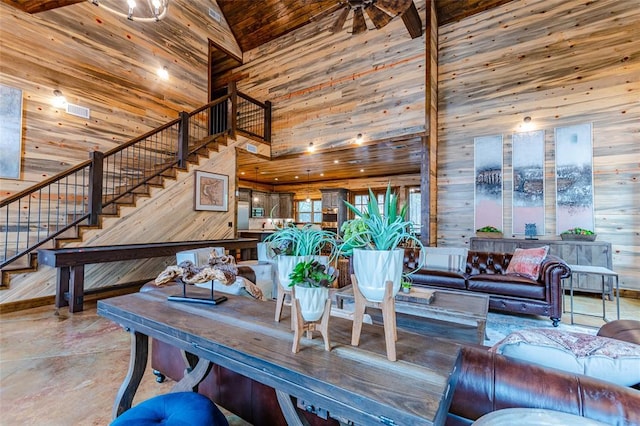 living area featuring concrete flooring, wood walls, a towering ceiling, and stairs