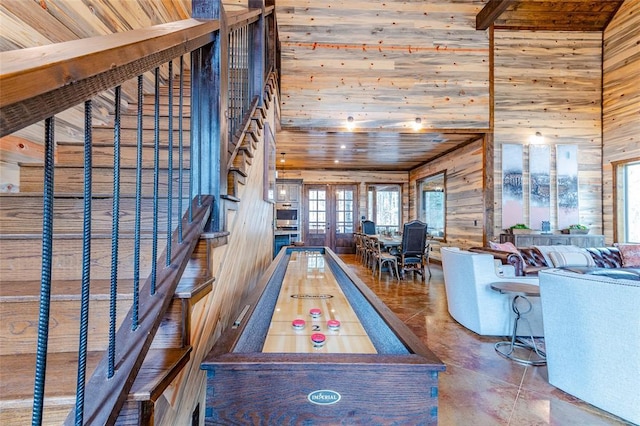 rec room with french doors, wooden ceiling, a towering ceiling, and wooden walls