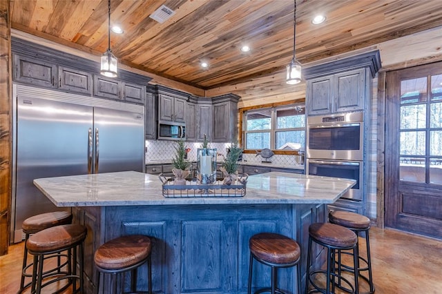 kitchen featuring a spacious island, appliances with stainless steel finishes, backsplash, light stone countertops, and pendant lighting