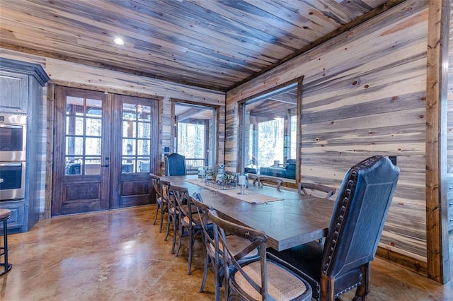 dining room featuring wooden ceiling, wooden walls, finished concrete floors, and french doors