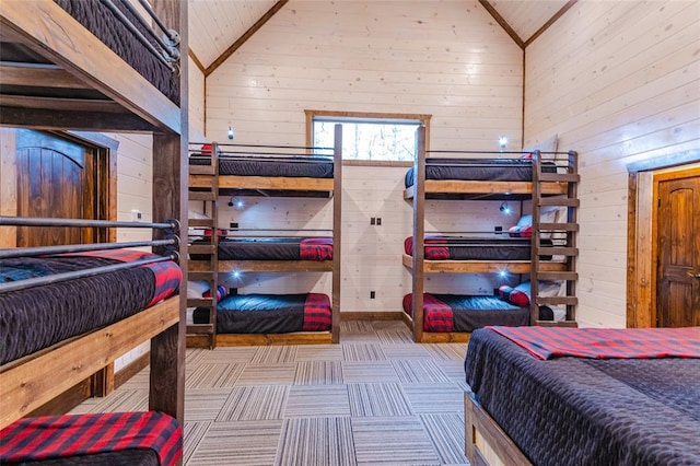 bedroom with high vaulted ceiling, carpet flooring, and wood walls