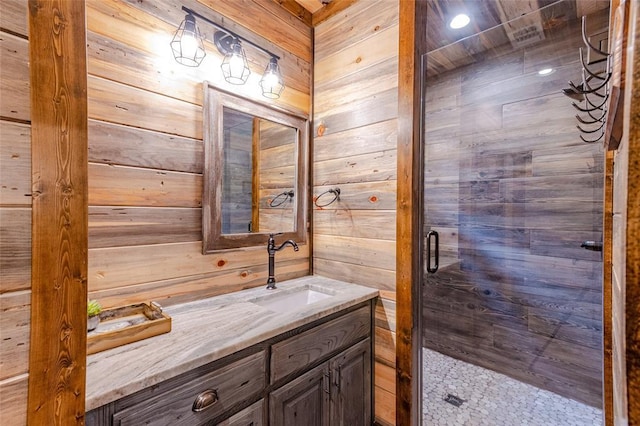 bathroom featuring wood walls, a shower stall, and vanity