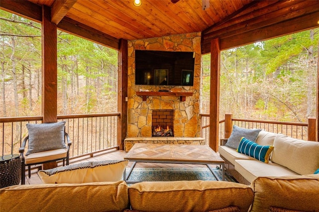 sunroom with vaulted ceiling, an outdoor stone fireplace, and wooden ceiling