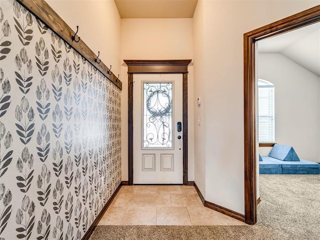 entrance foyer with light carpet, vaulted ceiling, and baseboards