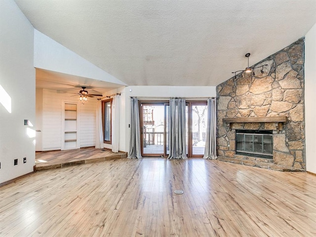 unfurnished living room with lofted ceiling, a stone fireplace, a textured ceiling, and hardwood / wood-style flooring