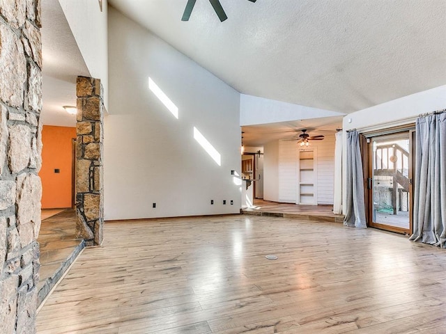 unfurnished living room with vaulted ceiling, a textured ceiling, wood finished floors, and a ceiling fan