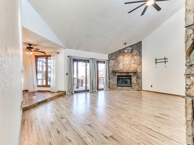 unfurnished living room featuring wood-type flooring, ceiling fan, a stone fireplace, a textured ceiling, and high vaulted ceiling