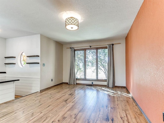 empty room featuring hardwood / wood-style flooring, a textured ceiling, and a textured wall