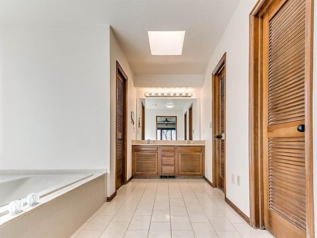 full bathroom featuring a sink, a skylight, a garden tub, and a closet