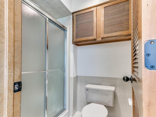 full bath featuring a stall shower, wainscoting, tile walls, and toilet