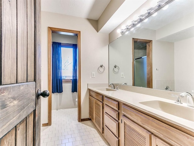 full bathroom with double vanity, toilet, a sink, and tile patterned floors