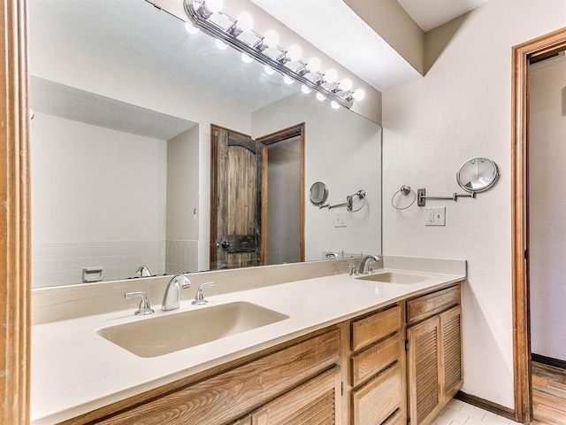 bathroom with double vanity, baseboards, and a sink