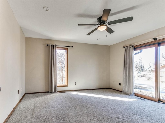 carpeted empty room with ceiling fan, visible vents, and baseboards