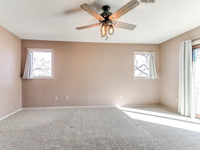 empty room with ceiling fan, carpet, a wealth of natural light, and baseboards