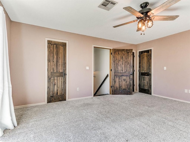 unfurnished bedroom featuring carpet floors, baseboards, visible vents, and a ceiling fan