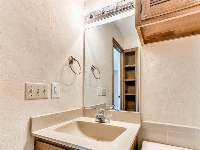 bathroom with a textured wall and vanity