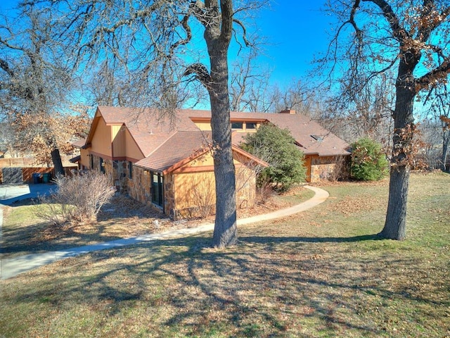 exterior space featuring stone siding and a front lawn