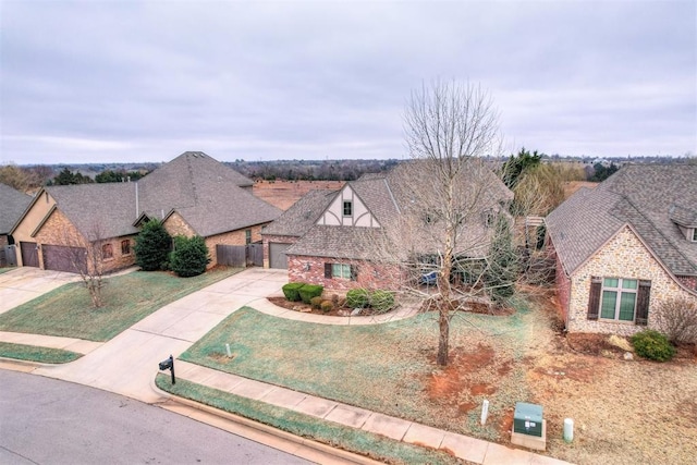 view of front facade featuring a shingled roof, brick siding, fence, driveway, and a front yard