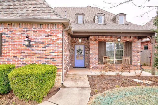 property entrance with a shingled roof and brick siding