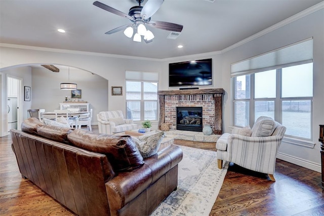 living room featuring arched walkways, visible vents, crown molding, and wood finished floors