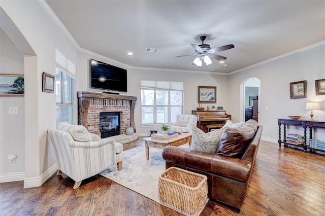 living area with arched walkways, visible vents, ornamental molding, wood finished floors, and baseboards