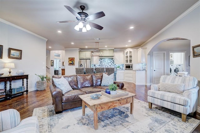 living room featuring arched walkways, crown molding, washing machine and clothes dryer, and wood finished floors