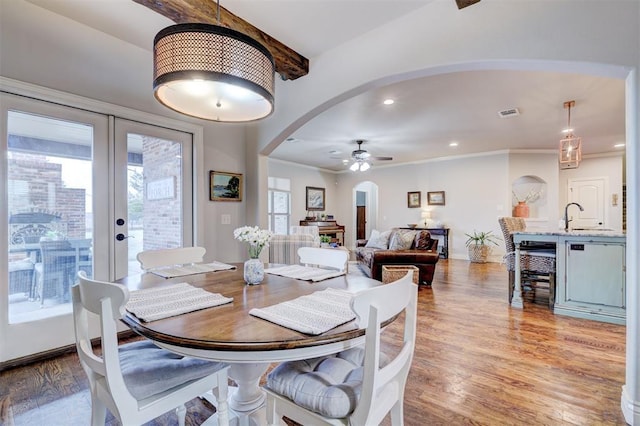 dining room with arched walkways, light wood-style flooring, recessed lighting, baseboards, and french doors