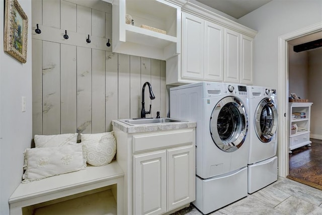 washroom with cabinet space, a sink, and independent washer and dryer