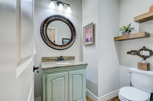 bathroom featuring toilet, vanity, and baseboards