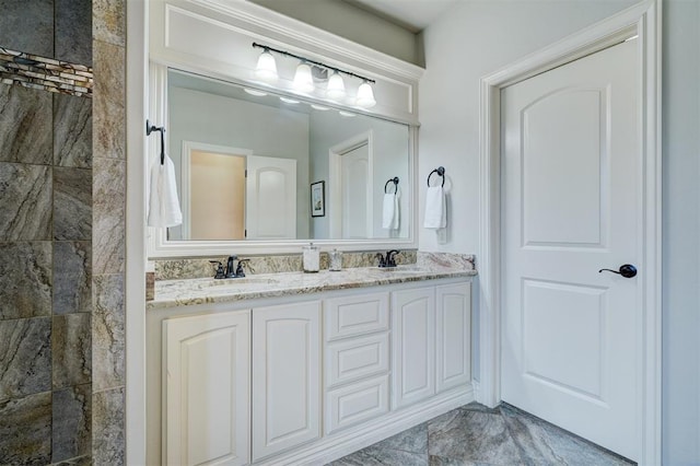 bathroom with a tile shower, double vanity, and a sink