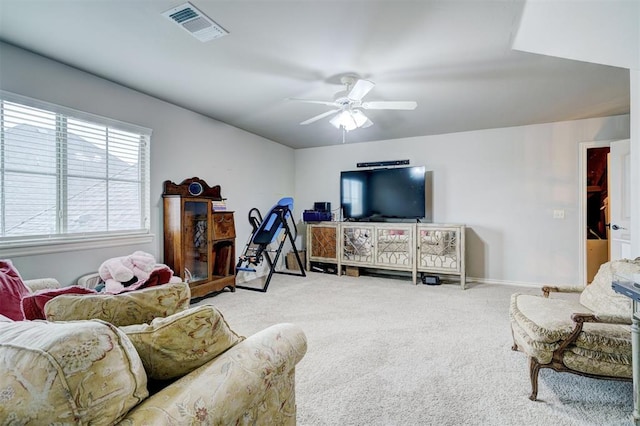 living area featuring carpet, visible vents, and ceiling fan