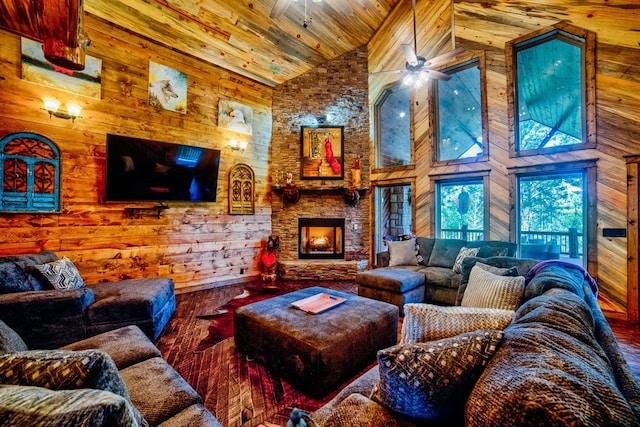 living room featuring wood walls, wood finished floors, and a stone fireplace