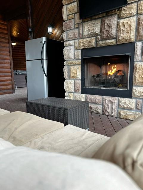 details featuring freestanding refrigerator, a stone fireplace, and wood finished floors