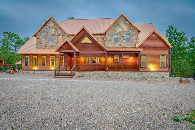 view of front of property featuring stone siding, faux log siding, and metal roof