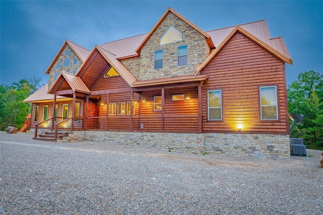 view of front of property with metal roof, stone siding, log veneer siding, and covered porch