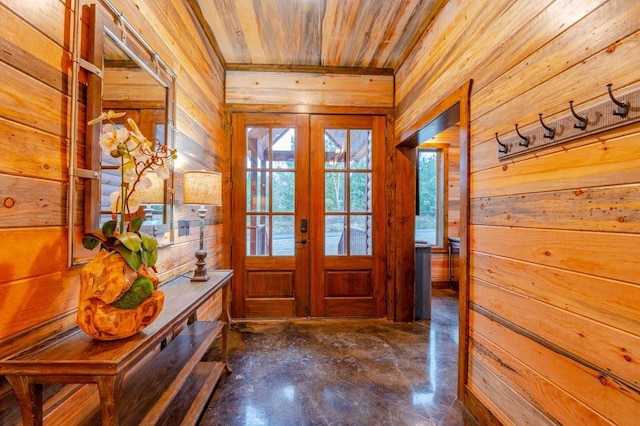 entryway with french doors, concrete floors, wood ceiling, and wooden walls