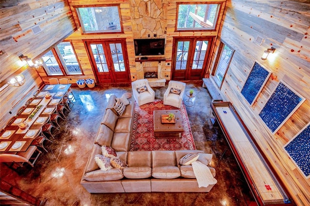 living area with a towering ceiling, wood walls, and french doors