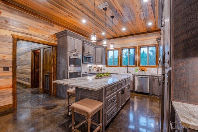 kitchen with wooden ceiling, appliances with stainless steel finishes, light stone counters, a center island, and wood walls