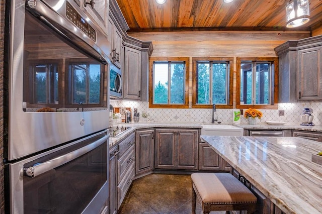 kitchen with light stone countertops, wood ceiling, stainless steel appliances, and decorative backsplash