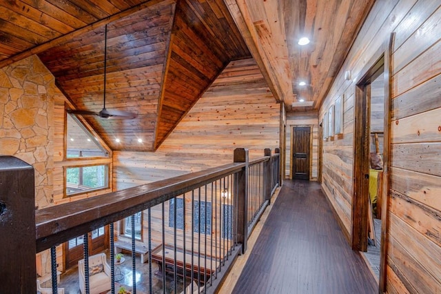 corridor featuring wood ceiling, wooden walls, dark wood finished floors, and an upstairs landing