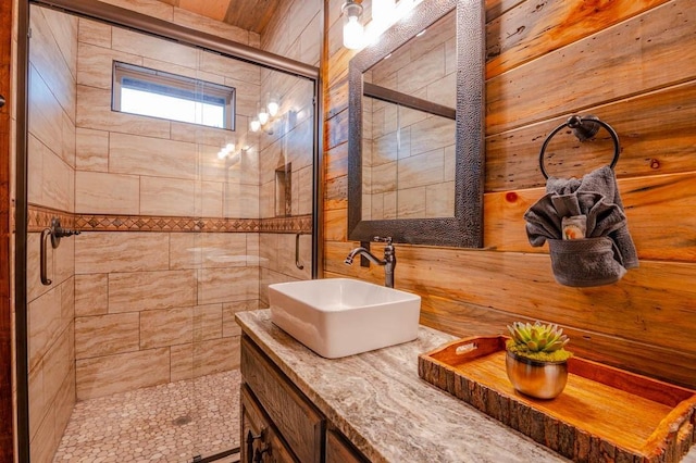 full bathroom featuring wood walls, a shower stall, and vanity