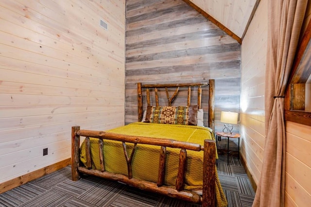 bedroom with wood walls, carpet, and visible vents