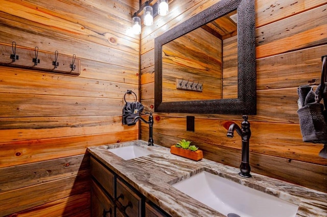 full bath featuring a sink, wood walls, and double vanity