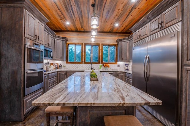 1080 N Lukfata Trail Rd, Broken Bow, OK 74728 - kitchen with appliances with stainless steel finishes, wood ceiling, a breakfast bar area, backsplash, and light stone countertops