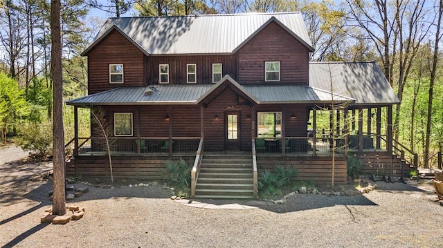 view of front of home featuring metal roof, stairway, a porch, and log veneer siding