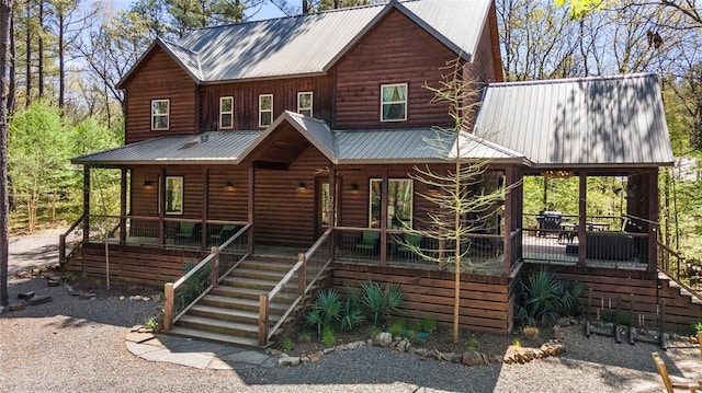 view of front of home featuring covered porch, metal roof, stairway, and log veneer siding