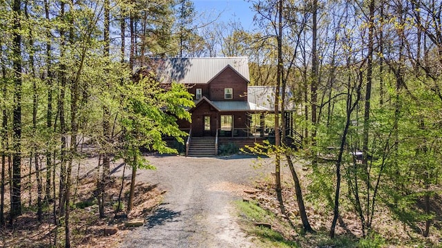 chalet / cabin featuring dirt driveway, metal roof, a porch, and stairway