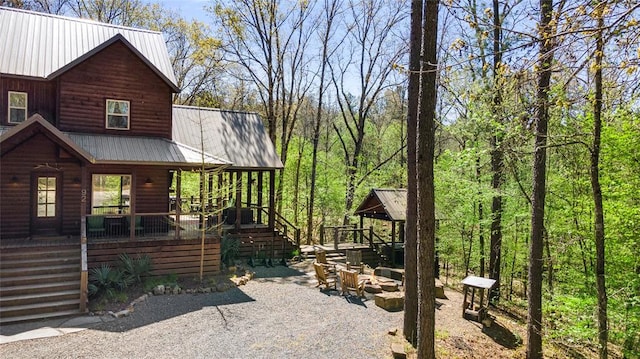 view of side of property featuring a fire pit, metal roof, covered porch, and faux log siding